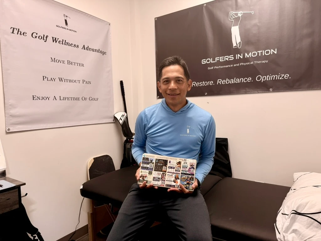 A customer at Golfers in Motion holding Dustin’s SpotDrops Georgetown postcard