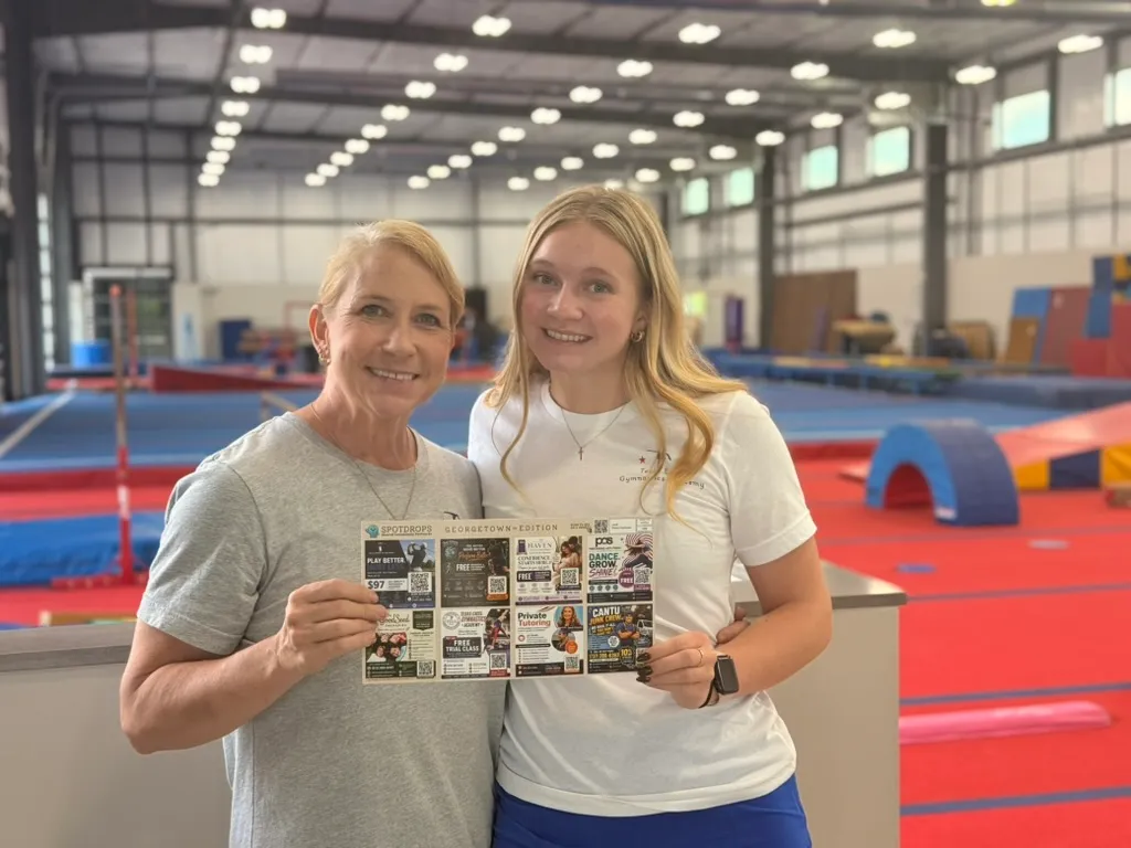 Two customers at a gymnastics facility holding Dustin’s SpotDrops Georgetown postcard